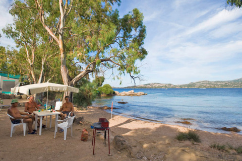 Beachfront camping scene at Centro Vacanze Isuledda in Sardinia, Italy, with people relaxing and nature views.
