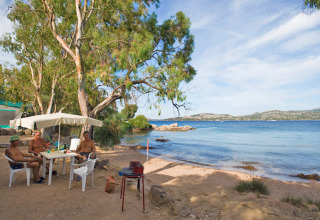 Beachfront camping scene at Centro Vacanze Isuledda in Sardinia, Italy, with people relaxing and nature views.