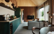 Interior de casa tiny moderna con cocina, sala de estar y grandes ventanales en Unbrick One, Brinckerduyn.