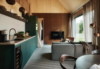 Interior de casa tiny moderna con cocina, sala de estar y grandes ventanales en Unbrick One, Brinckerduyn.
