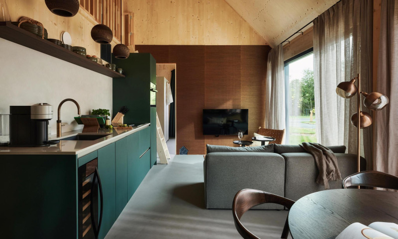 Interior de casa tiny moderna con cocina, sala de estar y grandes ventanales en Unbrick One, Brinckerduyn.