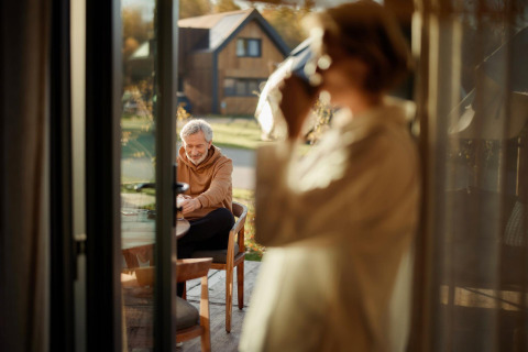 Older couple enjoying a peaceful morning at a table outside a Unbrick One tiny house in Brinckerduyn, Netherlands.