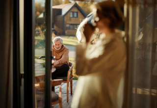 Older couple enjoying a peaceful morning at a table outside a Unbrick One tiny house in Brinckerduyn, Netherlands.
