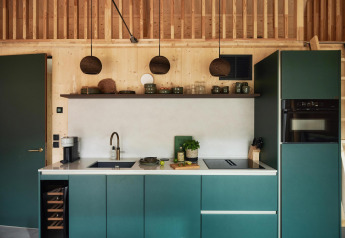 Modern tiny kitchen at Unbrick One | Sauna in Brinckerduyn, Netherlands, with green cabinets and wood walls.