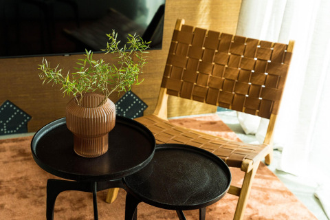 Silla moderna y mesas redondas con un jarrón de ramas verdes en una acogedora casa diminuta en los Países Bajos.