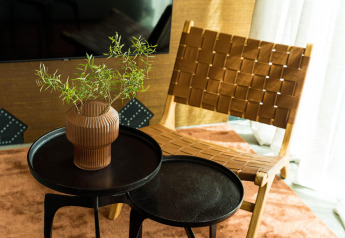 Modern chair and round side tables with vase and greenery in a cozy corner of a tiny house in the Netherlands.