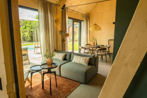 Interior luminoso de tiny house en Unbrick One, Brinckerduyn, con sofá, comedor y vista al patio en Países Bajos.