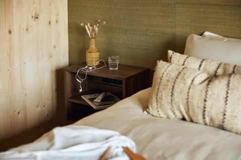 Bedroom interior in Unbrick One at Brinckerduyn, Netherlands, showing rustic decor, pillows and nightstand.