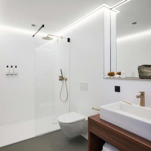 Baño moderno en Unbrick One, Países Bajos, con ducha a ras de suelo, inodoro suspendido y diseño minimalista.