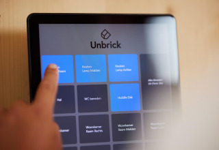 Finger touches smart home control screen with Unbrick interface in a Tiny House at Brinckerduyn, Netherlands.