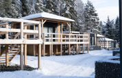 Cabañas de madera cubiertas de nieve en Edelweiss, junto al lago Ossiach, Austria, rodeadas de pinos nevados.
