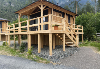 Trælodge Edelweiss ved Ossiacher See, Østrig, omgivet af bjerge og skov, med stor terrasse.