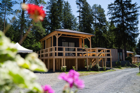 Edelweiss lodge at Ossiacher See in Austria, surrounded by tall trees and flowers on a bright sunny day.