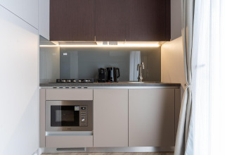 Kitchenette moderne à l’Edelweiss Lodge avec plaques, micro-ondes, cafetière et bouilloire électrique.