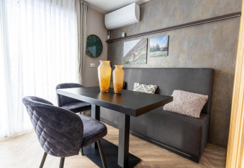 Moderne eethoek in Edelweiss lodge met zwarte stoelen, bank, sierkussens, vazen en wanddecoratie.