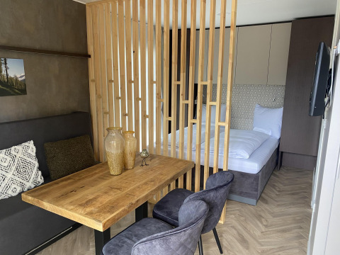Modern lodge room at Edelweiss by Ossiacher See in Austria with wood table, chairs, and separate bed area.