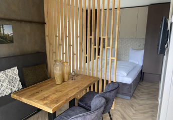 Chambre moderne à la lodge Edelweiss au lac Ossiacher See, Autriche, avec table en bois et espace lit séparé.