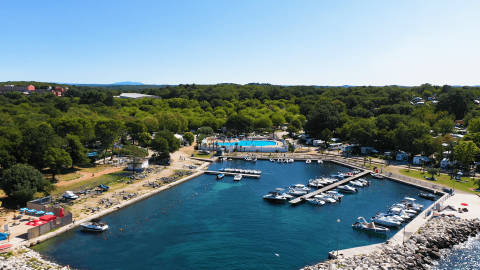 Luftaufnahme vom Camping Zelena Laguna in Istrien, Kroatien mit Yachthafen, Booten und Pool inmitten von Wald.