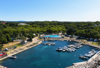 Luftfoto af Camping Zelena Laguna i Istrien, Kroatien med marina, både og swimmingpool omgivet af grøn skov.