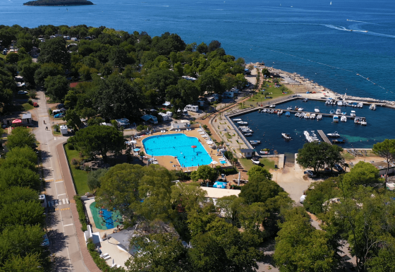 Vista aerea del Camping Zelena Laguna in Istria, Croazia, con piscina, porto turistico e il mare sullo sfondo.