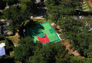 Luftfoto af basketballbane omgivet af træer i Camping Zelena Laguna, Istrien, Kroatien på en solrig dag.