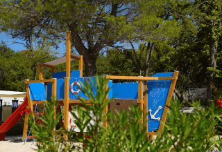 Kinderspielplatz mit blauem Holzspielschiff und Rutsche, umgeben von Bäumen im Camping Zelena Laguna, Istrien.
