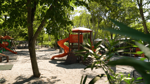 Parco giochi per bambini con scivoli all’ombra degli alberi presso il Camping Zelena Laguna, Istria.