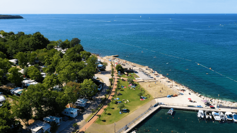 Luftaufnahme vom Camping Zelena Laguna in Istrien, Kroatien, mit Strand, Wohnwagen und klarem blauem Meer.