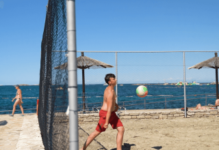 Dreng spiller strandvolley på Camping Zelena Laguna i Istrien, Kroatien med hav og strand i baggrunden.