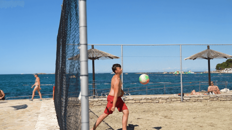 Jongen speelt beachvolleybal op Camping Zelena Laguna in Istrië, Kroatië aan zee.