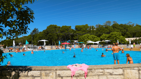 Piscina al aire libre con bañistas, sombrillas y árboles en Camping Zelena Laguna en Istria, Croacia.