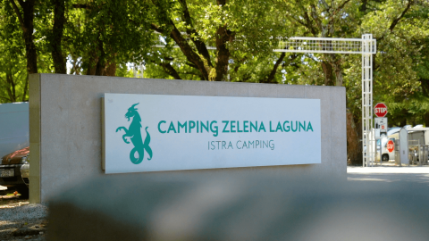 Cartello d'ingresso di Camping Zelena Laguna, parco vacanze in Istria, Croazia, circondato da alberi.