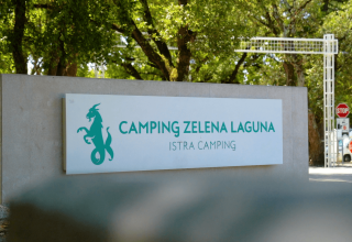 Indgangsskilt til Camping Zelena Laguna feriested i Istrien, Kroatien, omgivet af træer og parkering.