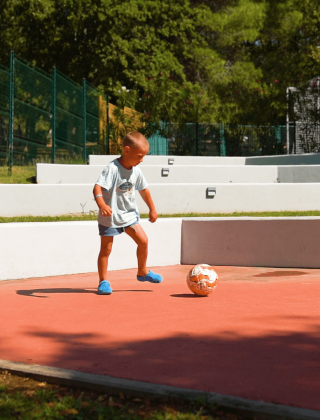 Un niño juega al fútbol en el área de juegos del Camping Zelena Laguna en Istria, Croacia, bajo el sol.