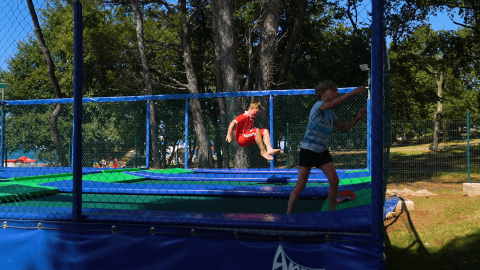 Bambini che giocano e saltano su un trampolino all'aperto al Camping Zelena Laguna, parco vacanze in Istria, Croazia.