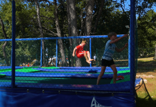 Bambini che giocano e saltano su un trampolino all'aperto al Camping Zelena Laguna, parco vacanze in Istria, Croazia.