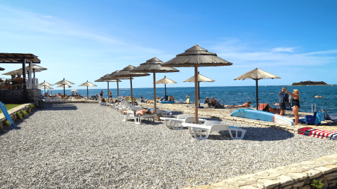 Strand mit Sonnenschirmen und Liegen im Camping Zelena Laguna, einem Ferienpark in Istrien, Kroatien.