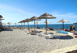 Spiaggia con ombrelloni e lettini al Camping Zelena Laguna, un villaggio vacanze in Istria, Croazia.