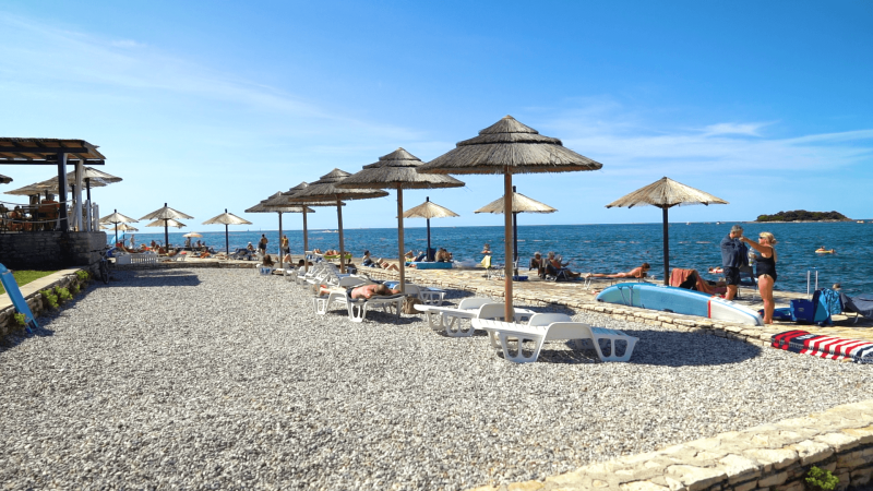 Beach with sun umbrellas and loungers at Camping Zelena Laguna, a holiday park in Istria, Croatia.