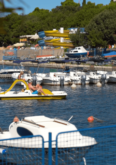 Barcos, hidropedales y turistas descansando en la marina del Camping Zelena Laguna, Istria, Croacia.