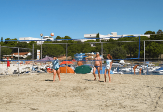 Folk spiller strandvolleyball på Camping Zelena Laguna, med telte og både i baggrunden i Istrien, Kroatien.