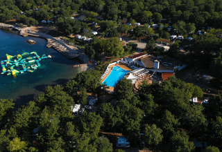 Vista aerea di Camping Bijela Uvala in Istria, Croazia, con piscina, spiaggia e parco acquatico galleggiante.