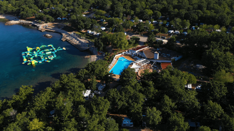 Vista aerea di Camping Bijela Uvala in Istria, Croazia, con piscina, spiaggia e parco acquatico galleggiante.