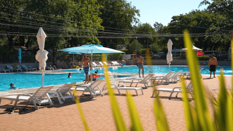 Piscina al aire libre con tumbonas, sombrillas y huéspedes en Camping Bijela Uvala, Istria, Croacia.