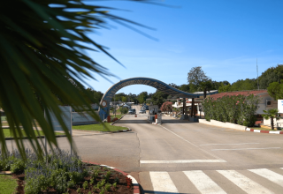 Indgangsporten til Camping Bijela Uvala, en feriepark i Istrien, Kroatien, omgivet af grønne planter.