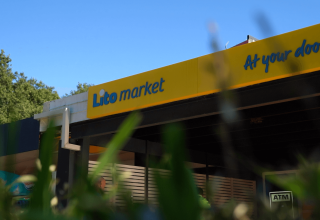 Foto del Lito Market presso Camping Bijela Uvala, Istria, Croazia, con insegna gialla e blu del negozio.