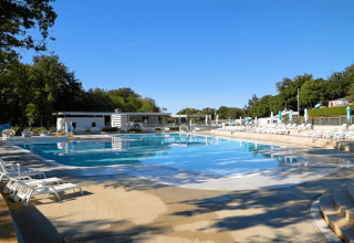 Udendørs swimmingpool med liggestole og parasoller på Camping Bijela Uvala i Istrien, Kroatien på en solrig dag.