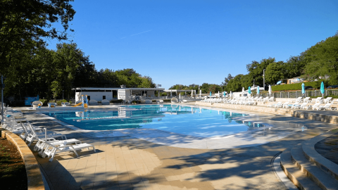 Outdoor swimming pool with sun loungers and umbrellas at Camping Bijela Uvala in Istria, Croatia on a sunny day.