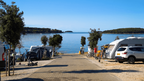 Caravanas y coches en Camping Bijela Uvala con vistas al mar y a islas verdes en Istria, Croacia.