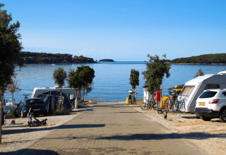Caravan e auto al Camping Bijela Uvala con vista sul mare e le isole verdi in Istria, Croazia.